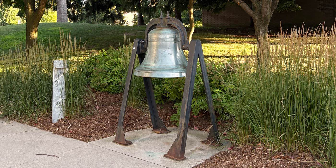 Historic town bell surrounded by plants
