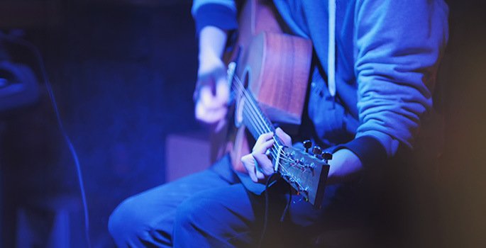 close up of man's hands playing a guitar