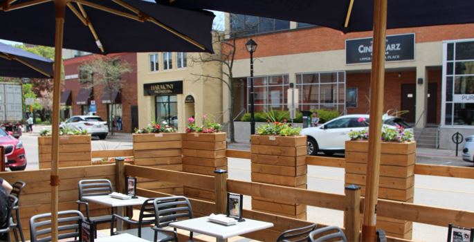 on-street temporary wooden patio with tables, chairs and umbrellas