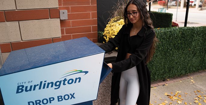 lady placing an envelope in the City's drop box