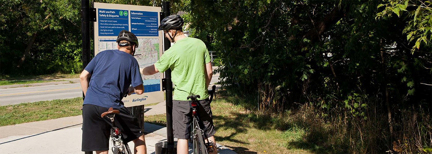 Community Trails Strategy Update Two young men on bicycles look at a trail map sign