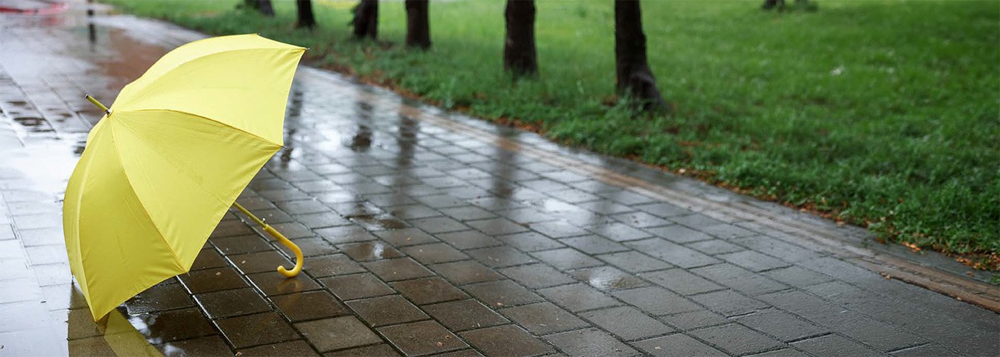 Consider flood protection programs to keep your home safe Puddles on brick path with yellow umbrella