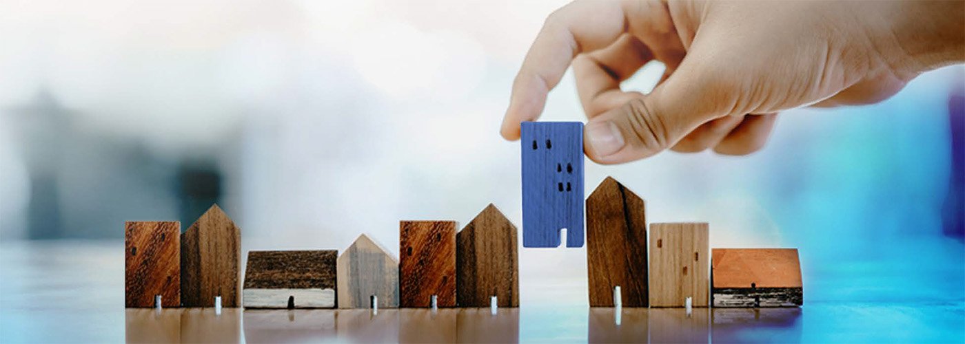 City continues to invest in housing in Burlington Hand placing several wooden toy houses in a row
