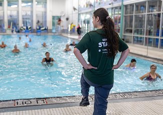 Adults participating in drop-in aquatic fitness program led by recreational instructor.