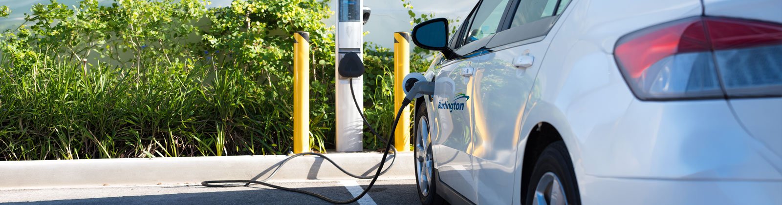 White municipal vehicle parked and plugged into an EV charger