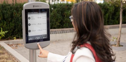 Person checking bus times at an outdoor schedule post.